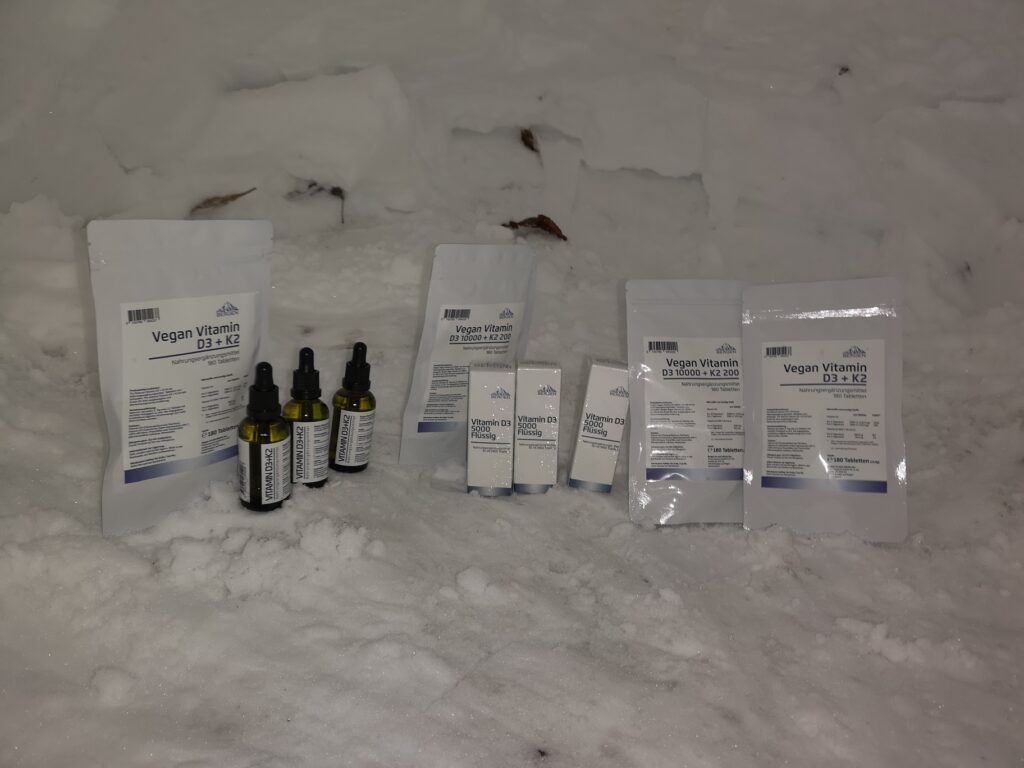 Vitamin-D3- und D3-K2-Produkte als Tropfen und Tabletten im Schnee